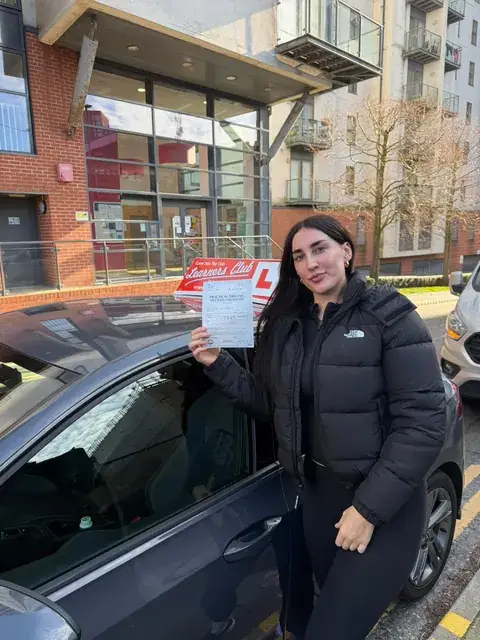 A Learners' Club pupil holding their driving test pass certificate