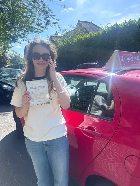 A Learners' Club pupil holding their driving test pass certificate